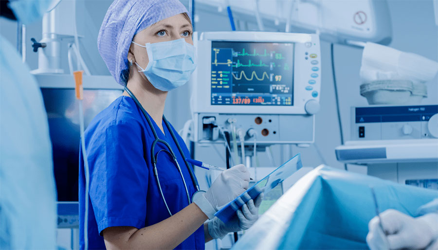 Operating Room Anesthesiologist Looks and Monitors and Controls Patient's Vital Signs